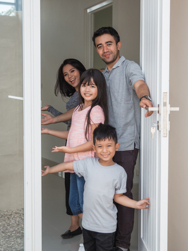Father and his three children stand in a white, open door frame, welcoming people out of sight.